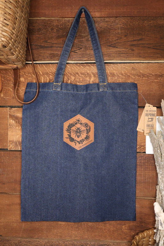Blue denim tote bag with a leather patch on a wooden surface